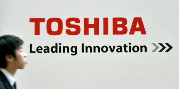 In this photo taken on Dec. 11, 2008, a man walks by a corporate logo of Japan's top chipmaker Toshiba Corp. at the latest environmentally friendly technologies and products fair