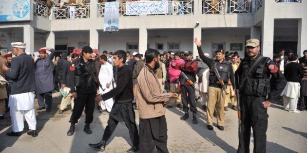 Pakistani police and onlookers gather in front of a hospital following an attack by gunmen at Bacha Khan university in Charsadda, about 50 kilometres from Peshawar, on January 20, 2016. At least 21 people died in an armed assault on a university in Pakistan on January 20, where witnesses reported two large explosions as security forces moved in under dense fog to halt the bloodshed. AFP PHOTO /Hasham AHMED / AFP / HASHAM AHMED (Photo credit should read HASHAM AHMED/AFP/Getty Images)