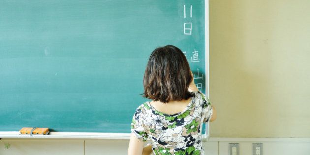 woman writing on black board, Japan.