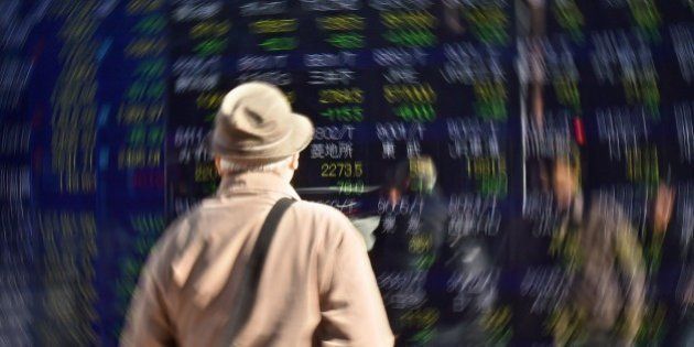 A pedestrian looks at a screen showing movements for the Tokyo Stock Exchange in Tokyo on January 14, 2016. The benchmark Nikkei 225 index at the Tokyo Stock Exchange tumbled 2.68 percent, or 474.68 points, to 17,240.95 at the close, after losing nearly four percent at one stage. AFP PHOTO / KAZUHIRO NOGI / AFP / KAZUHIRO NOGI (Photo credit should read KAZUHIRO NOGI/AFP/Getty Images)