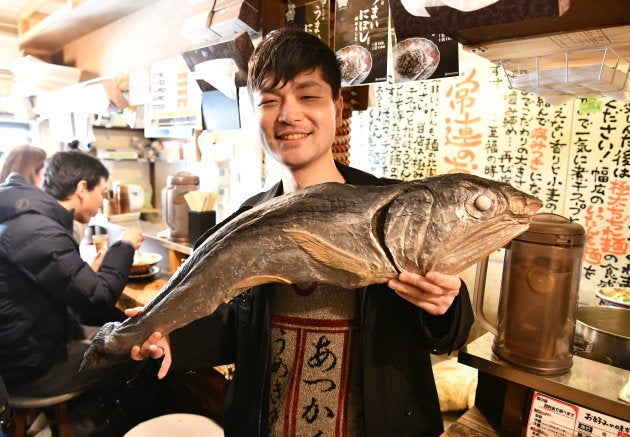 煮干しの巨大彫刻を持つ大曽根悠二郎さん＝東京・新宿