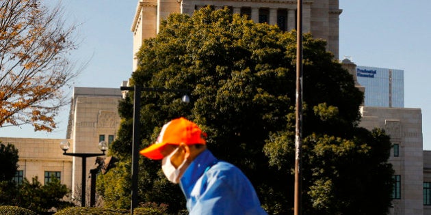 A worker blows leaves off the pavement outside the Diet building, the seat of Japan's parliament, in Tokyo, December 14, 2014. Prime Minister Shinzo Abe's party looks set for a huge win on Sunday in a low-voltage election that will allow the conservative leader to claim a fresh mandate for his reflationary policies to revive Japan's long-stagnant economy. REUTERS/Thomas Peter (JAPAN - Tags: POLITICS ELECTIONS)