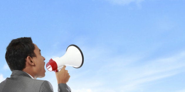 business man shouting using megaphone under the blue sky