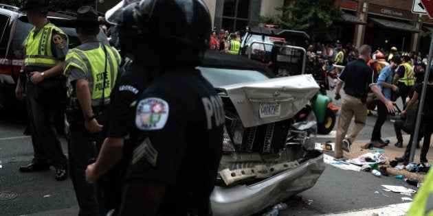 First responders stand by a car that was struck when a car drove through a group of counter protesters at the