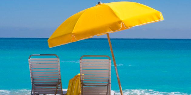 'Yellow Beach umbrella and deck chairs on the beach on a clear day on South beach, Miami'