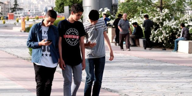 Iranian youth use their mobile phones as they walk at a park in Tehran, Iran, May 16, 2017. REUTERS/TIMA ATTENTION EDITORS - THIS IMAGE WAS PROVIDED BY A THIRD PARTY. FOR EDITORIAL USE ONLY.