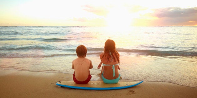 Caucasian children sitting on surfboard on tropical beach