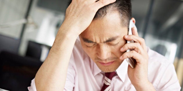 asian businessman talking on cellphone looking sad and frustrated.