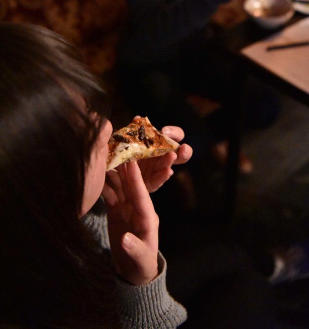 コオロギがのったピッツァを食べる参加者の女性