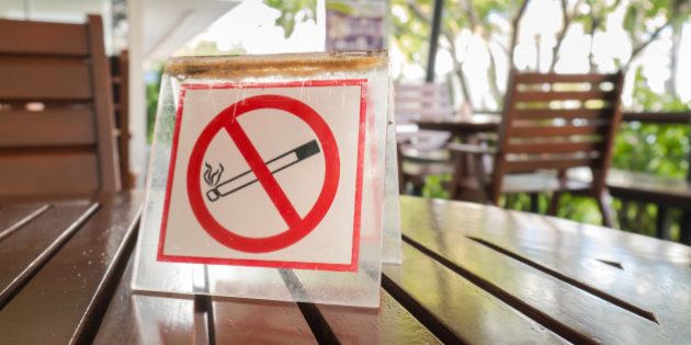 No smoking sign displayed on the wooden table in the public cafe