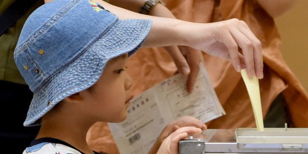 A boy watches as his mother cast her ballot at a polling station in Tokyo on July 10, 2016. Japanese voters headed to the polls July 10 to cast their ballot in a parliamentary election with Prime Minister Shinzo Abe's ruling party expected to cruise to victory despite lukewarm support. / AFP / TORU YAMANAKA (Photo credit should read TORU YAMANAKA/AFP/Getty Images)