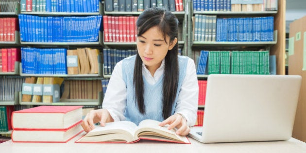 Student with open book reading it in college library