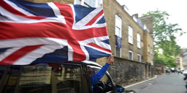 A taxi driver holds a Union flag, as he celebrates following the result of the EU referendum, in central London, Britain June 24, 2016. REUTERS/Toby Melville