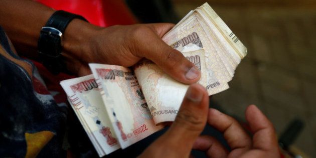 A man counts 500 and 1000 Indian rupee banknotes outside a branch of Bank of India in Mumbai, India, November 10, 2016. REUTERS/Danish Siddiqui