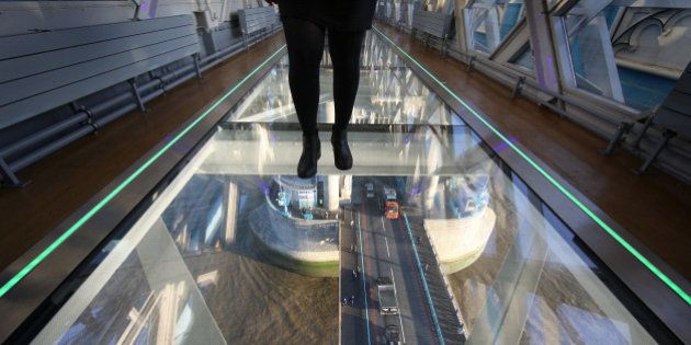 LONDON, ENGLAND - NOVEMBER 10: A visitor crosses Tower Bridge's new glass walkway on November 10, 2014 in London, England. Unveiled today the glass floor panels along the bridge's high-level walkways weigh 300 kgs each, cost Â£1m and will give visitors a new view over the historic bridge crossing The River Thames. (Photo by Peter Macdiarmid/Getty Images)