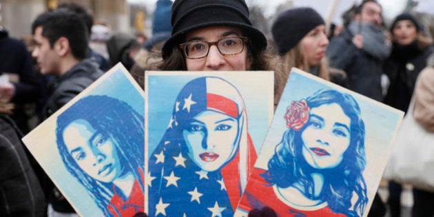 TOPSHOT - An anti-Trump protester hold signs during a demonstration against Trump's policies in front of the Eiffel Tower in Paris, on February 4, 2017. US President Donald Trump lashed out on February 4, 2017 at a court ruling suspending his controversial ban on travelers from seven Muslim countries, dismissing it as 'ridiculous' and vowing to get it overturned. The order blocking the ban, issued late on February 3, 2017 by Seattle US District Judge James Robart, is valid across the United States, pending a full review of a complaint filed by Washington state's attorney general. / AFP / THOMAS SAMSON (Photo credit should read THOMAS SAMSON/AFP/Getty Images)