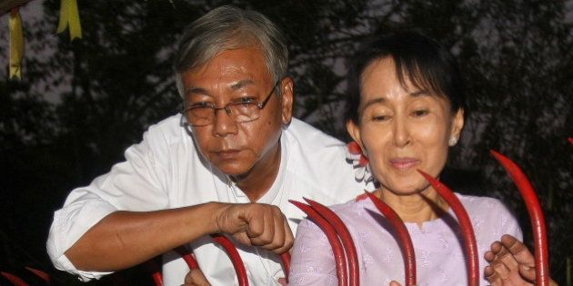 Myanmar's opposition leader Aung San Suu Kyi (R) appears with Htin Kyaw (L) a senior National League for Democracy (NLD) official, at the gate of her house in front of cheering supporters after her release in Yangon on November 13, 2010. Myanmar's democracy leader Aung San Suu Kyi walked free from the lakeside home that has been her prison for most of the past two decades, to the delight of huge crowds of waiting supporters. Waving and smiling, the petite but indomitable Nobel Peace Prize winner appeared outside the crumbling mansion where she had been locked up by the military junta for 15 of the past 21 years. AFP PHOTO/Soe Than WIN / AFP / Soe Than WIN (Photo credit should read SOE THAN WIN/AFP/Getty Images)