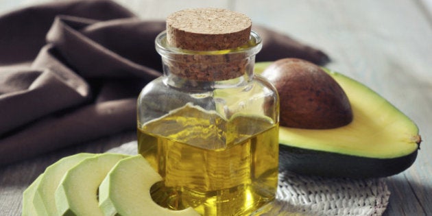 bottle of avocado essential oil with fresh avocado fruit closeup