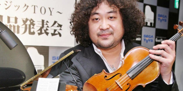 Tokyo, JAPAN: Japanese violinist Taro Hakase poses next to the world's smallest grand piano 'Grand Pianist', produced by Japan's toy maker Sega Toys, which have 88 working keys and can automatically play 100 pre-installed music songs after his session with auto-play piano in Tokyo 29 November 2006. The one sixth scaled grand piano will go on sale 01 April 2007 with a price of 47,000 yen (400 USD). AFP PHOTO / Yoshikazu TSUNO (Photo credit should read YOSHIKAZU TSUNO/AFP/Getty Images)