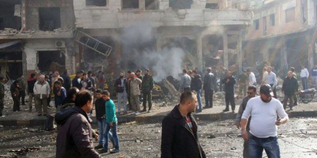 In this photo released by the Syrian official news agency SANA, Syrian citizens gather at the scene where two blasts exploded in the pro-government neighborhood of Zahraa, in Homs province, Syria, Sunday, Feb. 21, 2016. Two blasts in the central Syrian city of Homs killed more than a dozen people and injured many others in the latest wave of violence to hit the city in recent weeks, state TV said. (SANA via AP)