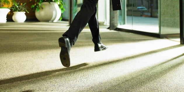 Businessman carrying briefcase leaving office building, rear view