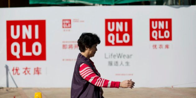 A woman walks past an advertisement for Uniqlo, operated by Fast Retailing Co., at a construction site in the Tianhe district of Guangzhou, Guangdong province, China, on Monday, Nov. 25, 2013. China is proposing the largest package of economic reforms since the 1990s to stoke growth in the worlds biggest emerging market. Photographer: Brent Lewin/Bloomberg via Getty Images