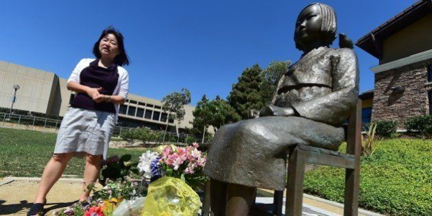 Activist Phyllis Kim of the Korean American Forum of California, stands beside the controversial Comfort Women Statue in Glendale, California on September 9, 2014, a day after reports that opponents of the statue have appealed the August decision by U.S District Judge Percy Anderson against removing the memorial dedicated to women who were coerced into sexual slavery during World War II by Japan, ruling the 1,100-pound memorial did not cause harm to the plaintiffs nor break any laws. The statue was installed at Glendale's Central Park in July 2013. AFP PHOTO / Frederic J. BROWN (Photo credit should read FREDERIC J. BROWN/AFP/Getty Images)