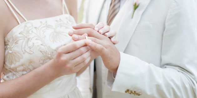 Bride putting ring on grooms finger