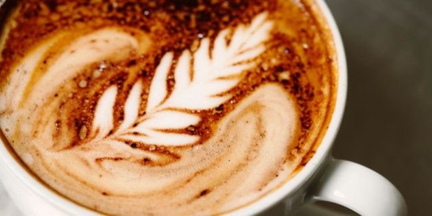 'A delicious cup of cafe mocha espresso on a stainless steel surface, beautifully poured with a signature rosette cream pattern.'