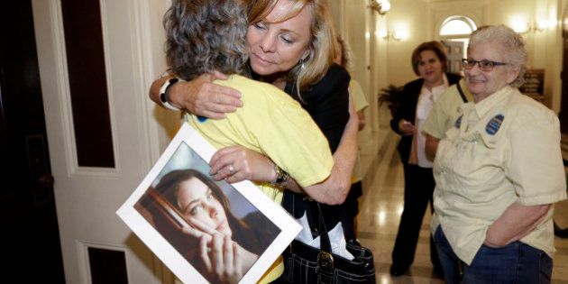 FILE - In this Sept. 9, 2015, file photo, Debbie Ziegler holds a photo of her daughter, Brittany Maynard, as she receives congratulations from Ellen Pontac, after a right-to die measure was approved by the Assembly in Sacramento, Calif. Maynard was a 29-year-old California woman with brain cancer who moved to Oregon to legally end her life. California lawmakers gave final approval Friday, Sept. 11, to a bill that would allow terminally ill patients to legally end their lives. The measure faces an uncertain future with Gov. Jerry Brown, a former Jesuit seminarian who has not said whether he will sign it. (AP Photo/Rich Pedroncelli, File)
