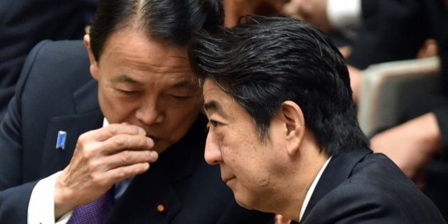 Japanese Minister Shinzo Abe (R) chats with Finance Minister Taro Aso (L) during a budget committee session of the House of Representatives at Parliament in Tokyo on February 25, 2015. Japan's farm minister resigned on February 23 after being accused of accepting illegal political funds, in a first blow to Prime Minister Shinzo Abe's new cabinet. AFP PHOTO / KAZUHIRO NOGI (Photo credit should read KAZUHIRO NOGI/AFP/Getty Images)
