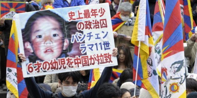 A protester holds a placard with portrait of Dalai Lama's choice for Panchen Lama, Gedhun Choekyi Nyima (top) during a peace march in Tokyo on March 14, 2009 to mark the 50th anniversary of Tibetan uprising against Chinese rule. Premier Wen Jiabao said on March 13, Tibet was prospering under Chinese rule, as he hit back at the Dalai Lama who this week said his Himalayan homeland had turned into 'hell on earth'. AFP PHOTO / TOSHIFUMI KITAMURA (Photo credit should read TOSHIFUMI KITAMURA/AFP/Getty Images)