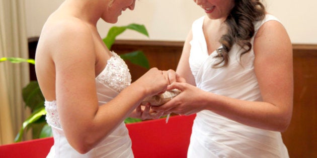 two brides getting married exchange rings in city hall