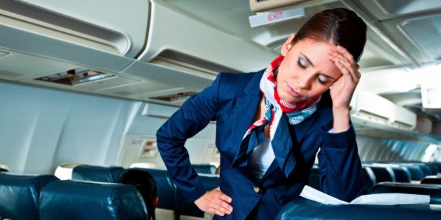 Young air stewardess suffering from headache on an airplane.