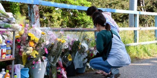 現場付近に置かれた花の前で手を合わせる人たち＝２０１８年５月１４日午後４時２６分、新潟市西区、田中奏子撮影