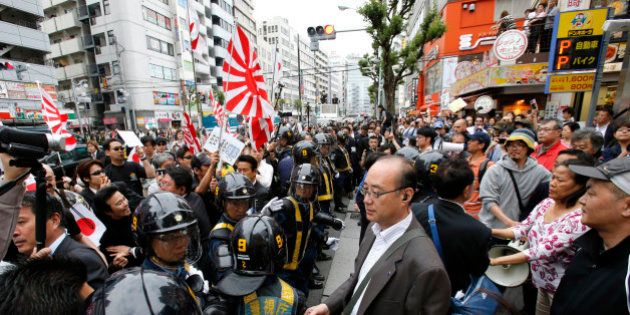 In this photo taken Sunday, May 19, 2013, nationalist protesters with Japanese flags and Japan's naval ensign march through a Tokyo street to denounce