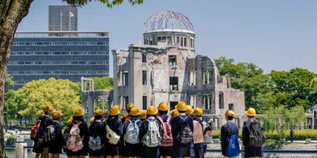 Children standing near Atomic Bomb memorial in Hiroshima, Japan. A-Bomb (Genbaku) Dome, Hiroshima, Japan. The Genbaku Dome also known as the Atomic Bomb Dome is now a symbol for peace within the Hiroshima Peace Memorial Park. The building designed by Jan Letzel, a Czech architect, was completed in 1915. The building was one of the few left standing when the first atomic bomb 'Little Boy' was dropped from the Enola Gay on August 6, 1945.