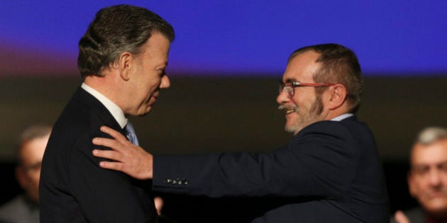 Colombia's President Juan Manuel Santos, left, shakes hands with with Rodrigo Londono, known as Timochenko, top leader of the Revolutionary Armed Forces of Colombia, FARC, after signing a revised peace pact at Colon Theater in Bogota, Colombia, Thursday, Nov. 24, 2016. An original accord ending the half century conflict was rejected by voters in a referendum last month. (AP Photo/Fernando Vergara)