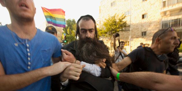 Ultra Orthodox Jew Yishai Schlissel is detained by plain-clothes police officers after he stabbed people during a gay pride parade in Jerusalem on Thursday, July 30, 2015. Schlisse was recently released from prison after serving a term for stabbing several people at a gay pride parade in 2005, a police spokeswoman said. (AP Photo/Sebastian Scheiner)
