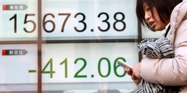 A woman walks past an electronic stock board showing Japan's Nikkei 225 in Tokyo, Wednesday, Feb. 10, 2016. Asian stock markets fell for a third consecutive day Wednesday, beset by nerves about shaky global growth, falling oil prices and possible capital shortfalls at major European banks. (AP Photo/Eugene Hoshiko)