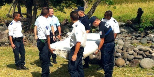 Police and gendarmes carry a piece of debris from an unidentified aircraft found in the coastal area of Saint-Andre de la Reunion, in the east of the French Indian Ocean island of La Reunion, on July 29, 2015. The two-metre-long debris, which appears to be a piece of a wing, was found by employees of an association cleaning the area and handed over to the air transport brigade of the French gendarmerie (BGTA), who have opened an investigation. An air safety expert did not exclude it could be a part of the Malaysia Airlines flight MH370, which went missing in the Indian Ocean on March 8, 2014. AFP PHOTO / YANNICK PITOU (Photo credit should read YANNICK PITOU/AFP/Getty Images)