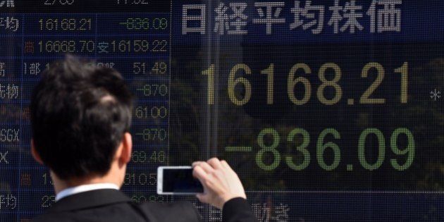 A businessman uses his smartphone to take pictures of an electric quotation board flashing the Nikkei key index of the Tokyo Stock Exchange (TSE) in front of a securities company in Tokyo on February 9, 2016. Tokyo shares tumbled nearly five percent, extending a global sell-off as a stronger yen dented exporters and after oil prices tanked again on fears of a deepening economic slowdown. AFP PHOTO/Toru YAMANAKA / AFP / TORU YAMANAKA (Photo credit should read TORU YAMANAKA/AFP/Getty Images)