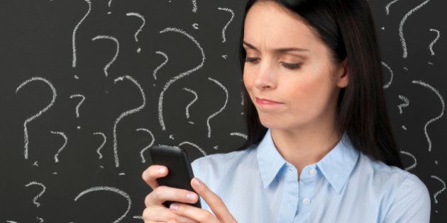 Mobile phone service concept - Woman texting with question marks on a blackboard.