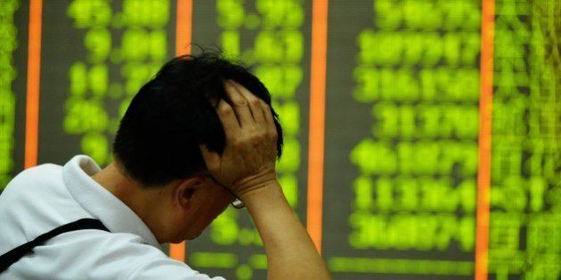 An investor rests on his arm before a screen that shows share prices in a security firm in Hangzhou, east China's Zhejiang province on July 27, 2015. China's benchmark Shanghai stock index slumped 5.22 percent in afternoon trade on July 27, dragged lower by worries over the economy. AFP PHOTO CHINA OUT (Photo credit should read STR/AFP/Getty Images)
