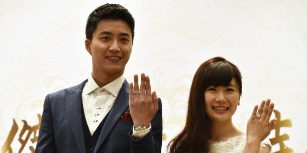 Taiwanese table tennis player Chiang Hung-chieh (L) and his Japanese wife Ai Fukuhara display their wedding rings during a press conference in Taipei on September 22, 2016.The couple made the announcement at a press conference saying they got married on September 1 in Tokyo. / AFP / SAM YEH (Photo credit should read SAM YEH/AFP/Getty Images)