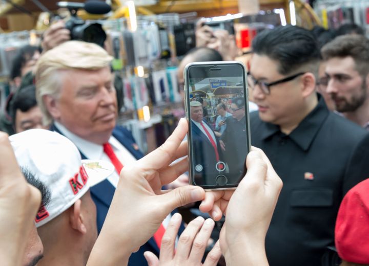 Kim Jong Un and Donald Trump impersonators Howard X (R) and Dennis Alan (L) are surrounded by onlookers as they arrive for a promotional event on June 9, 2018 in Singapore. / AFP PHOTO / TOH TING WEI