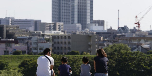 Visitors to the Tama River sit on a step in the Setagaya district of Tokyo, Japan, on Sunday, June 26, 2016. Packed trains, overcrowded schools and the country's longest waiting lists for preschool care are the norm in Setagaya, the most populous of Tokyo's 23 wards, as the Japanese continue their drift to the capital. Photographer: Yuya Shino/Bloomberg via Getty Images