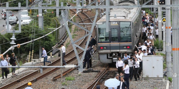 線路を歩いてＪＲ新大阪駅に向かう乗客＝１８日午前９時４分、大阪市淀川区 