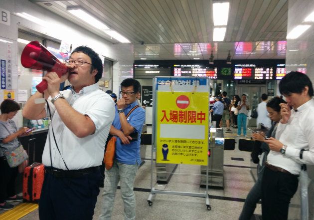 地震で鉄道が運転見合わせになり、安否確認を呼び掛ける駅員（左）＝１８日午前、ＪＲ大阪駅 撮影日：2018年06月18日