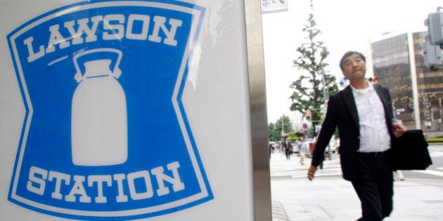 A man walks by signboard of a Lawson convenience store in Tokyo July 3, 2008. REUTERS/Kim Kyung-Hoon (JAPAN)